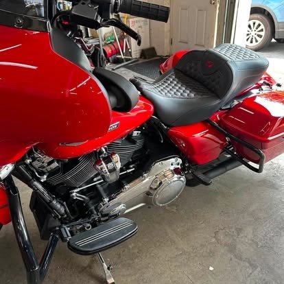 Seat, engine, and bags on a red Harley detailed by Tony